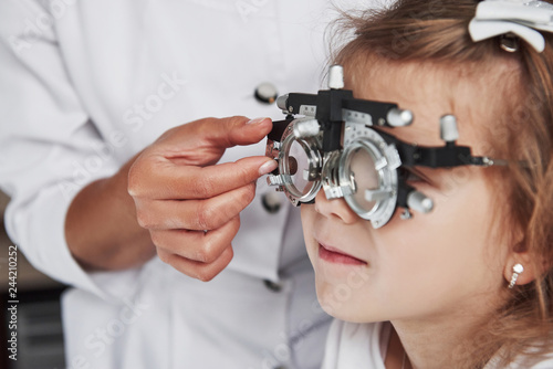 Focused photo of child in phoropter having testing his eyes in the doctor's office