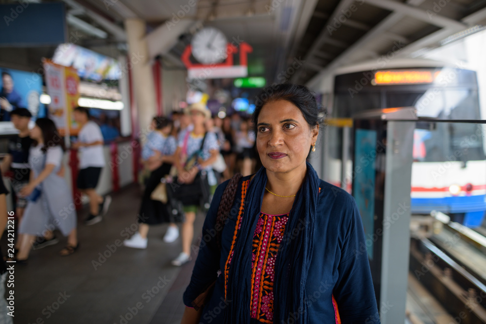 Mature beautiful Indian woman at train station thinking