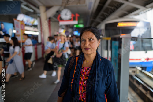 Mature beautiful Indian woman at train station thinking