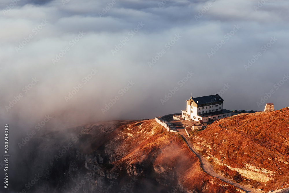 Fototapeta premium Lonely house. Hiking trail going near the hill with fog to the living building