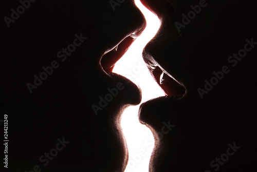 Two girls kissing in front of a white wall. photo