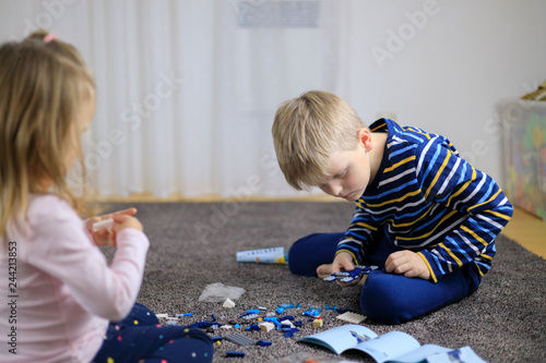 Two children playing with lots of colorful plastic blocks constructor.