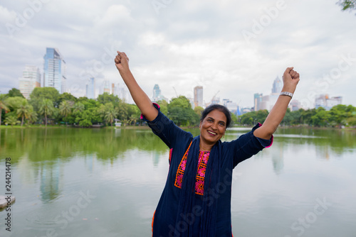 Mature beautiful Indian woman with arms raised in Lumpini park