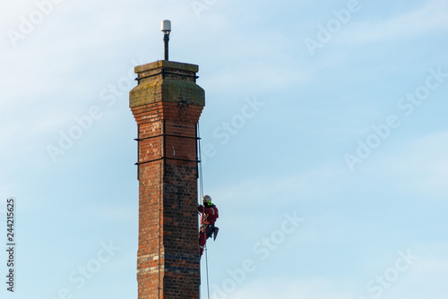 Tableau sur toile man doing a dangerous steeplejack job climbing down high brick tower with the ai