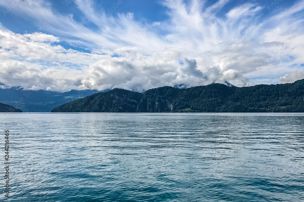 clear blue lake on a background of mountains, thick curly clouds over the lake