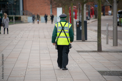 Photo traffic warden civil enforcement officer wearing reflective yellow vest walks do