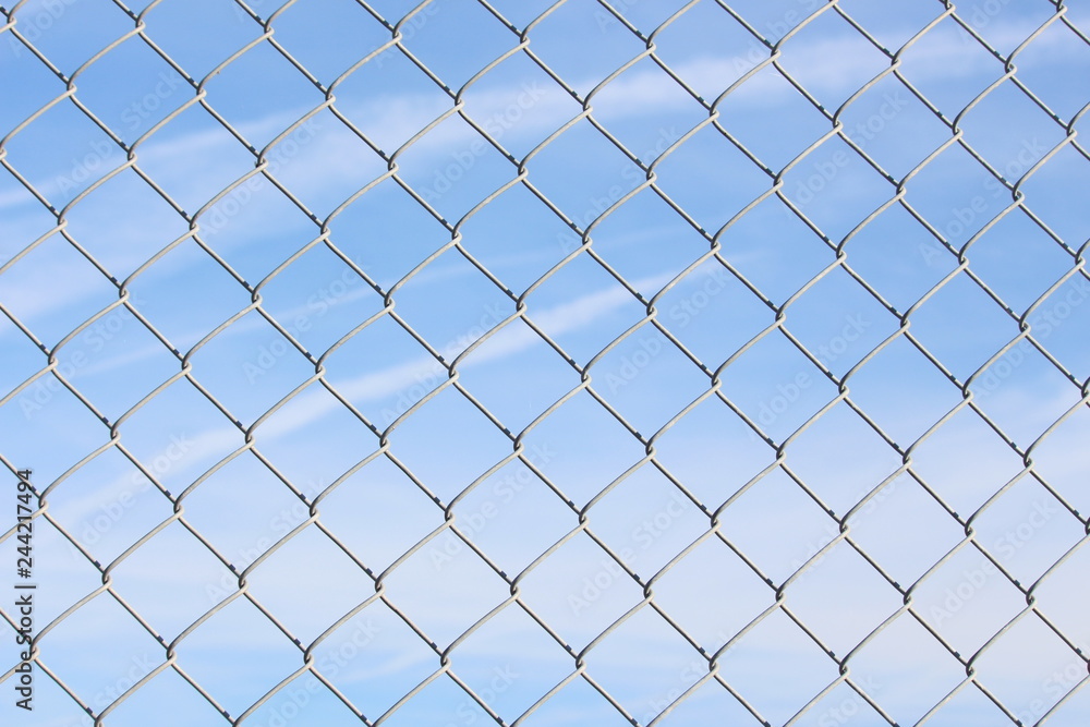 A close up photograph of a section of wire fencing, against a blue sky. Security, safety concept. Barrier A close up photograph of a section of wire fencing, against a blue sky. Security, safety concept. Barrier