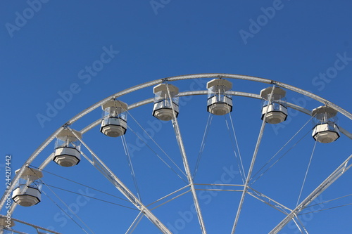 A photo of a section of a carnival ride, big wheel, against a blue summer sky. 