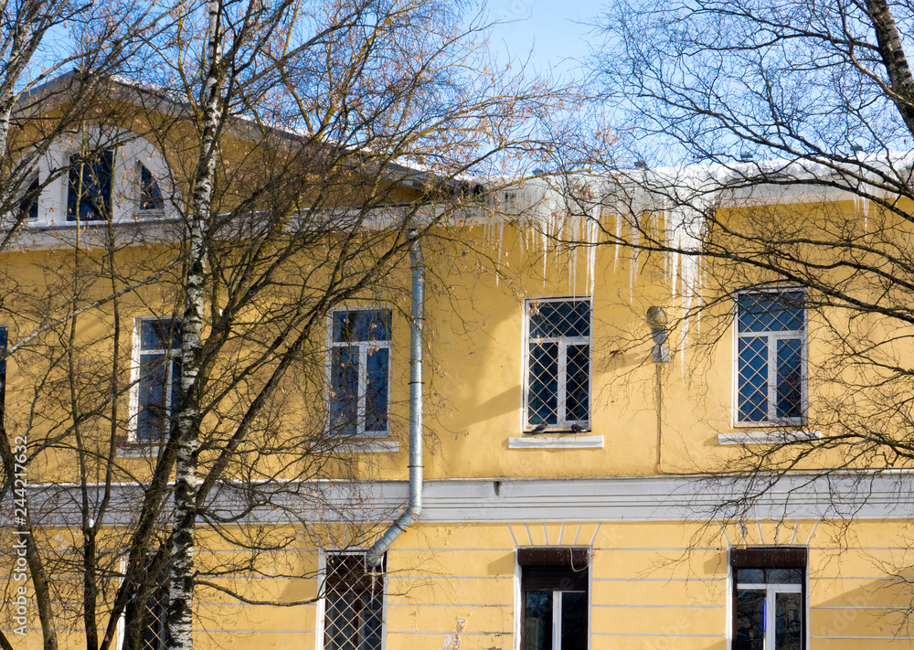 large, long, sharp icicles hang from the roof of the house, sparkling in the sun.. large, long, sharp icicles hang from the roof of the house, sparkling in the sun..