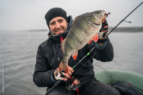 Happy fisherman with big perch fish trophy at boat