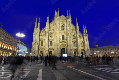 Gothic architecture of Milan Cathedral at night in Milan Italy with purposely blurred unrecognizable crowd of people in square