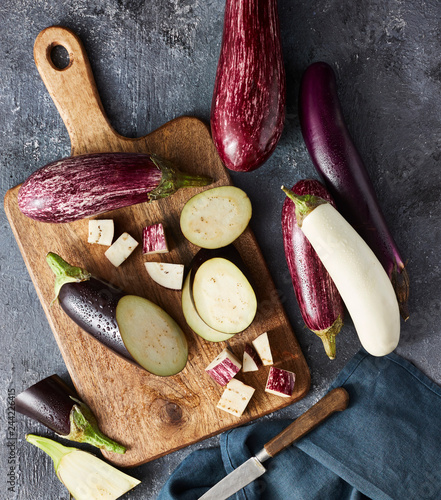 Overhead view of variety of raw eggplants on wooden cutting board