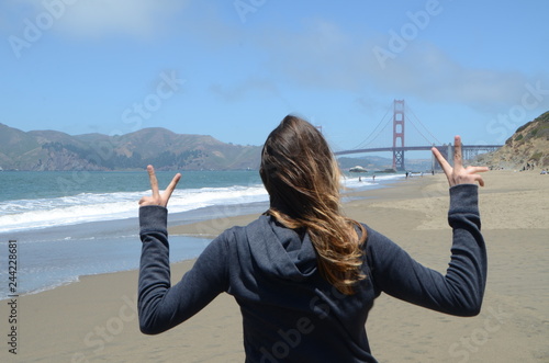 Segno della vittoria di ragazza dalla spiaggia al cospetto del Golden Gate 