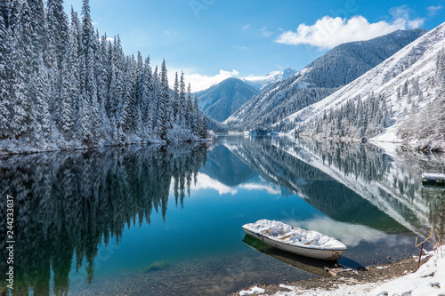 winter blue lake in the mountains, in the calm water of the lake reflecting mountains and trees