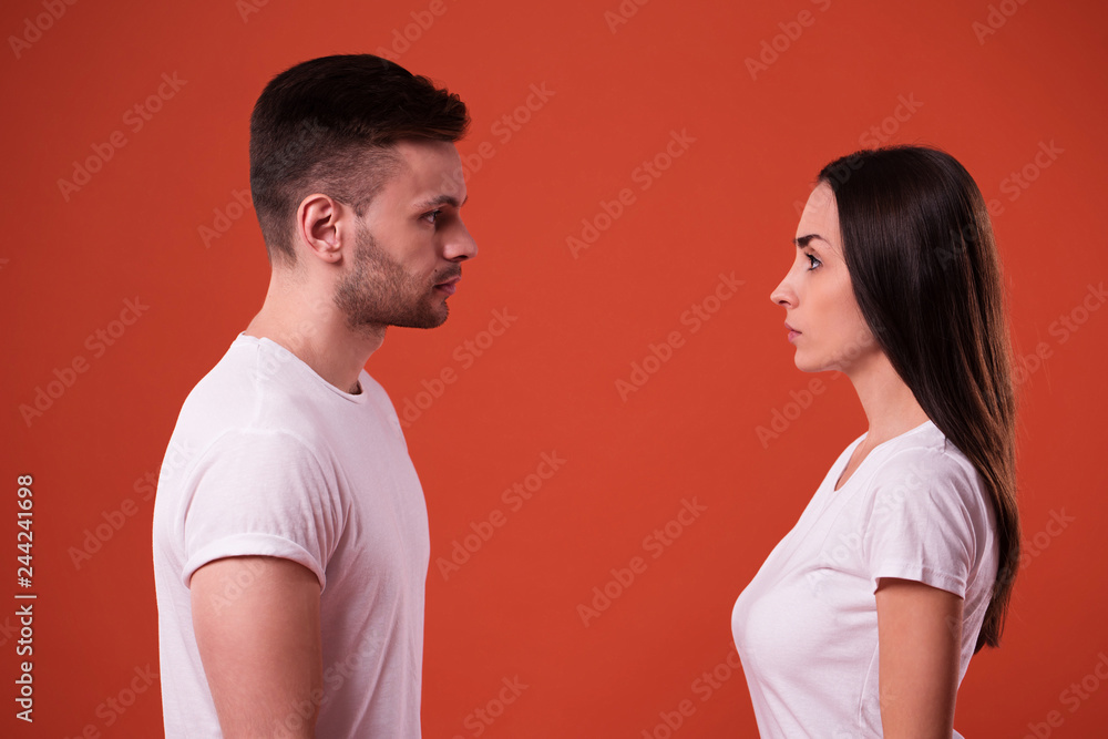 Side view photo of young serious couple standing face to face in studio Side view photo of young serious couple standing face to face in studio