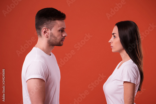 Foto Side view photo of young serious couple standing face to face in studio