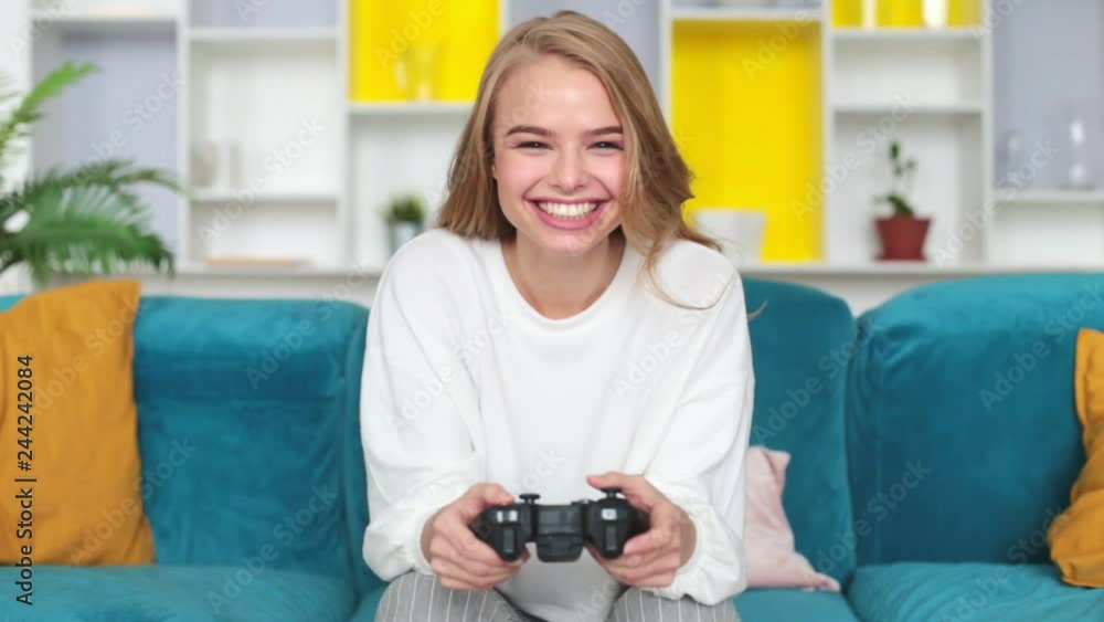 Happy young woman playing video games in living room. Happy young woman playing video games in living room.