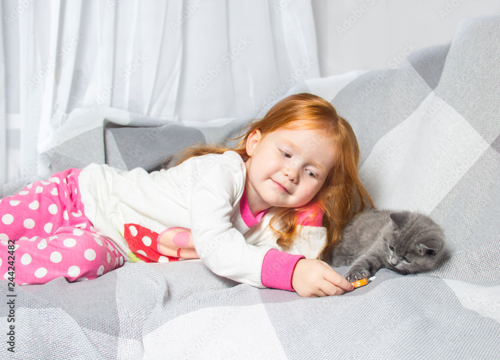 girl with red hair playing with a little kitten girl with red hair playing with a little kitten