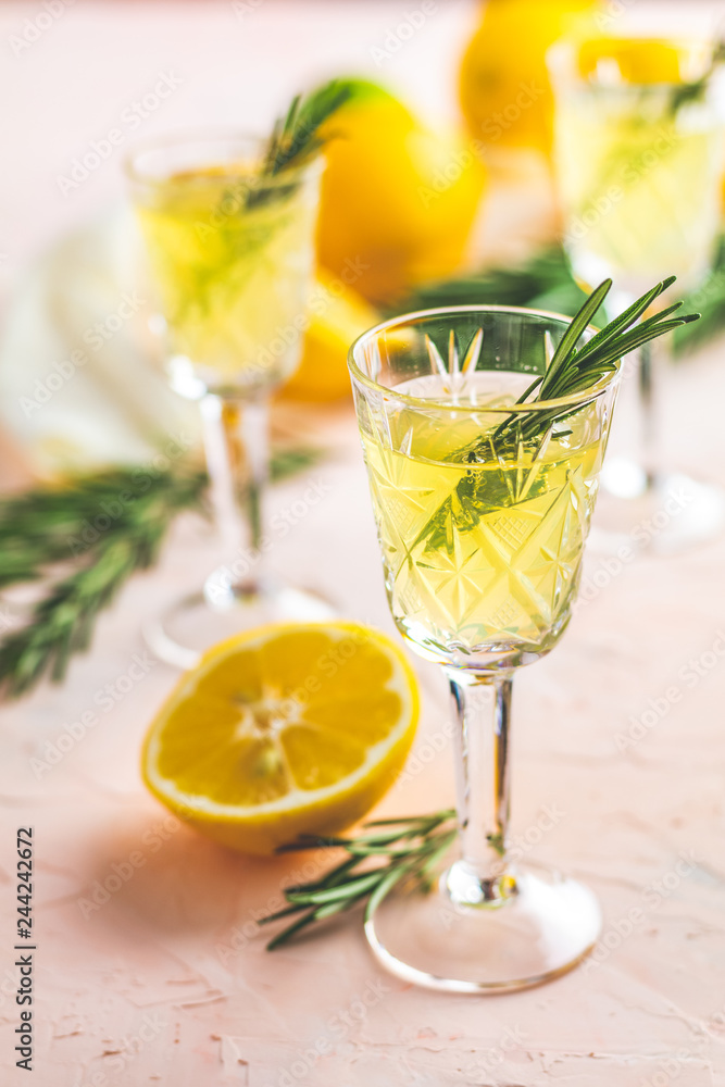Liqueur limoncello with pieces of lemon and rosemary herb Liqueur limoncello with pieces of lemon and rosemary herb