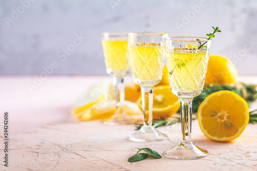 Foto Liqueur limoncello with pieces of lemon and rosemary herb