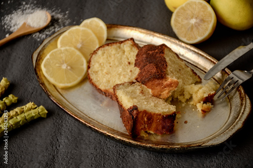 Classic lemon pound cake on rustic grey background with slices of lemon