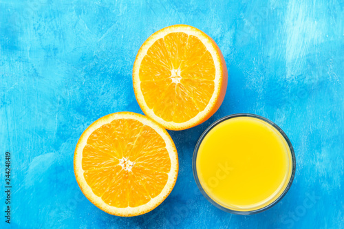 Orange fresh drink, glass of juice and ripe citrus fruits on a blue background, top view