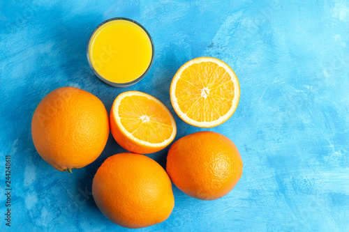 Orange fresh drink, glass of juice and ripe citrus fruits on a blue background, top view