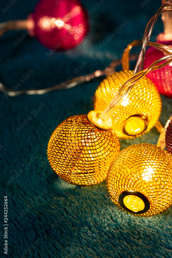 Naklejka premium Battery garland with metallic grid balls on blue blanket. Closeup view with blurred background.