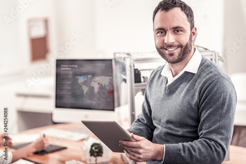 Smiling man in grey sweater working with tablet