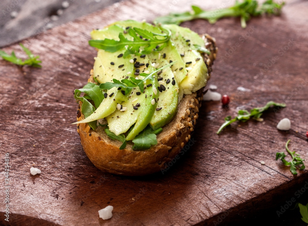 Bruschetta with avocado, rucola sesame and seeds on wooden table Bruschetta with avocado, rucola sesame and seeds on wooden table