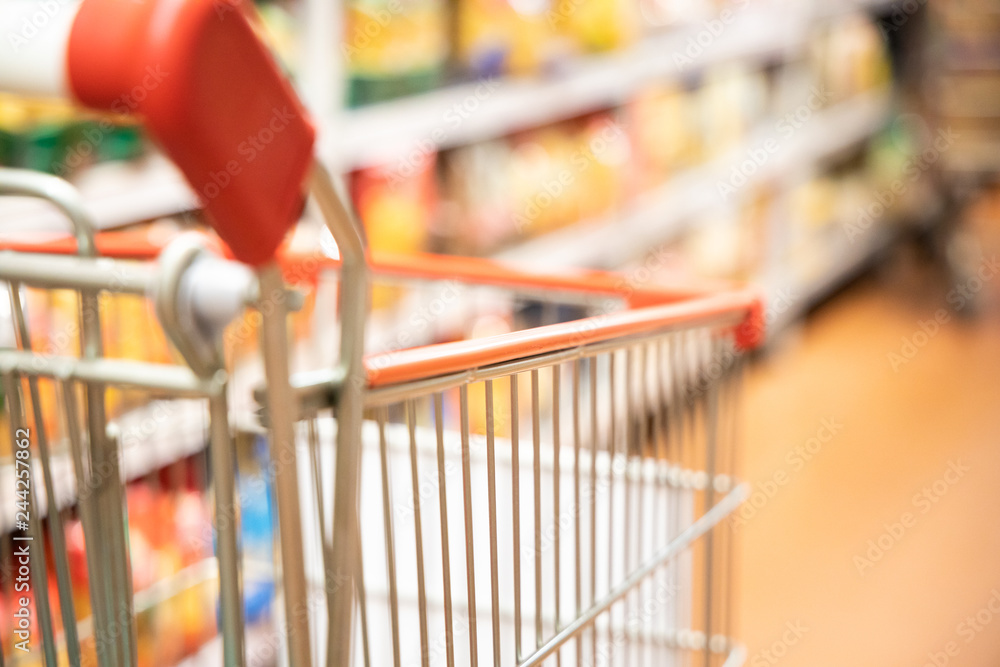 Shopping trolley cart with shallow DOF against supermarket aisle background