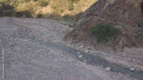 4k drone aerial footage of water stream on rocky river bed at sunset, with initial climb down into mountain canyon