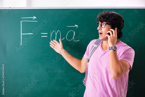 Young male physic standing in front of the green board photo