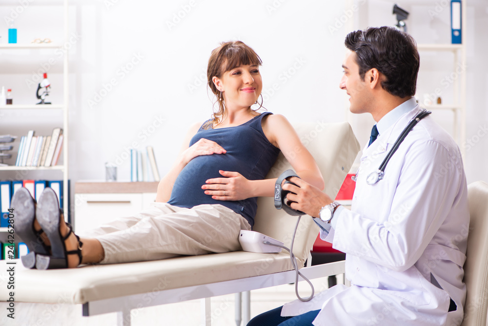 Young doctor checking pregnant woman's blood pressure