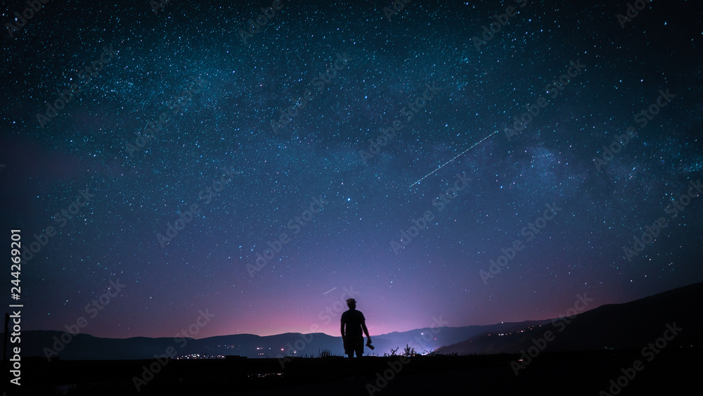 silhouette of man on top of mountain with stars
