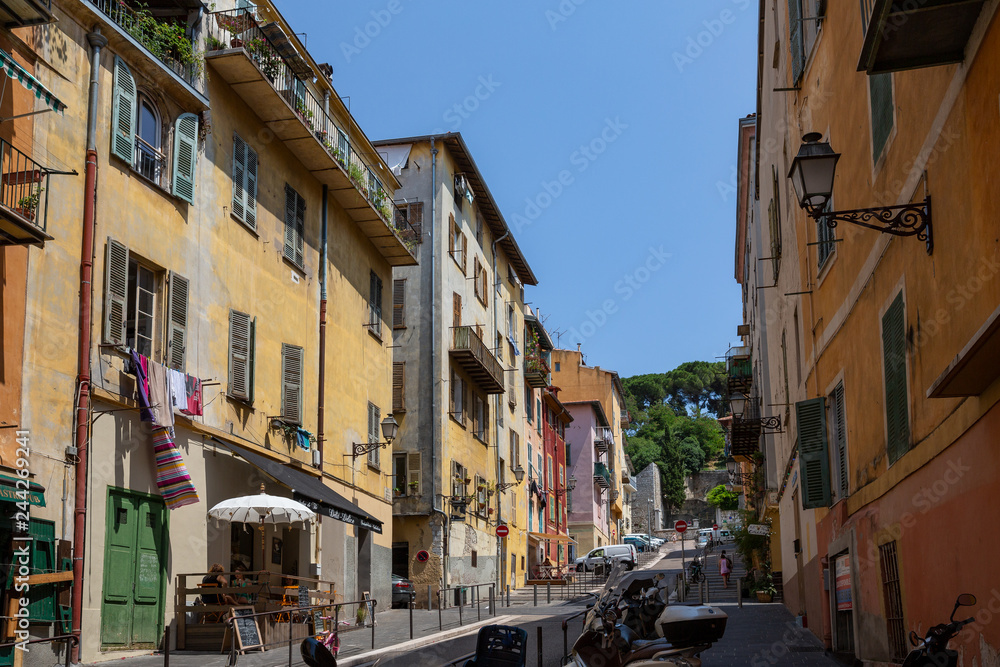 A typical colourful street in Nice, France, with beautiful apartment blocks above the shops and restaurants below