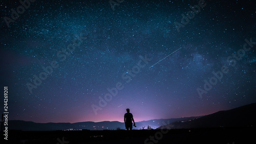 silhouette of man on top of mountain with stars
