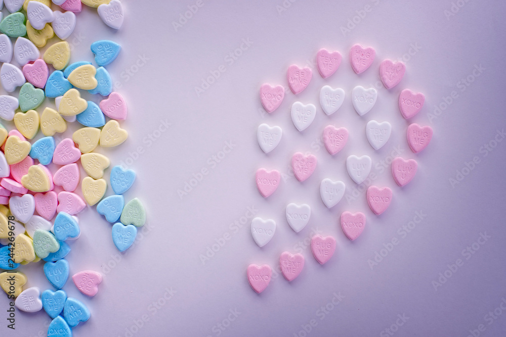 Valentine half pink heart candies with piles of pastel colourful candies Valentine half pink heart candies with piles of pastel colourful candies
