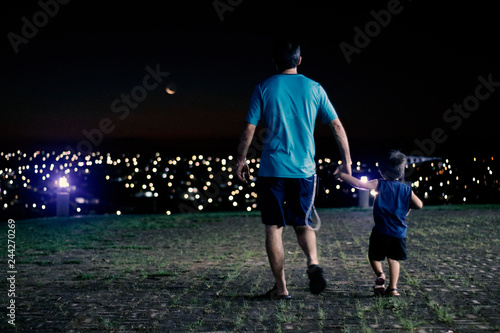 Father and son walking at night looking at city lights © Louriene