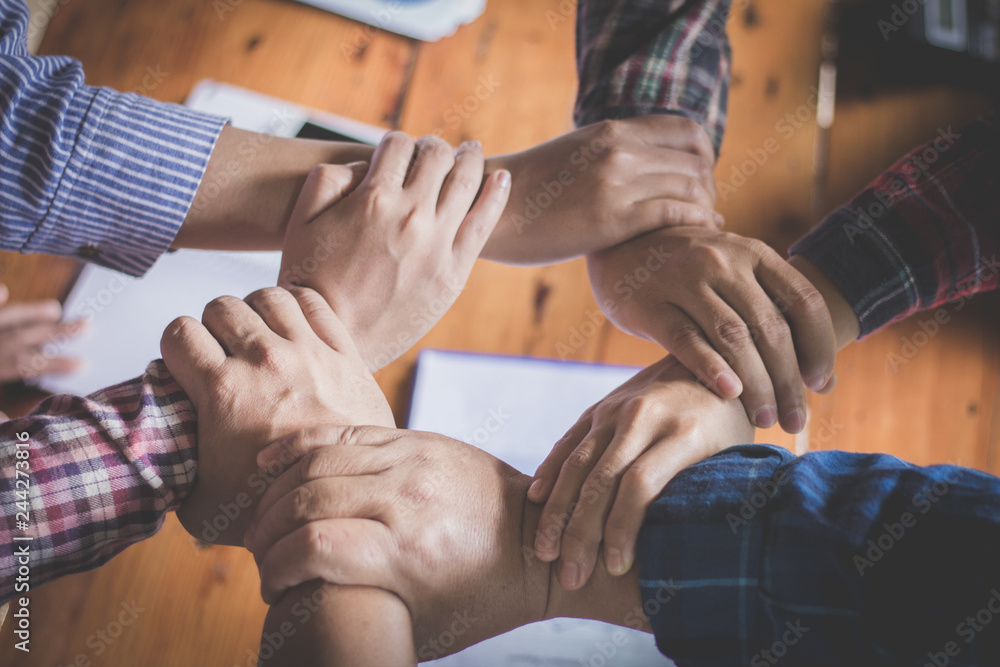 Fototapeta premium Young team putting hands up for new startup in creative office, Team Teamwork Togetherness Collaboration Co-working and teamwork concept