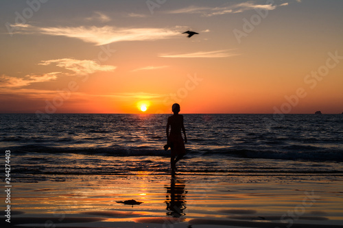 El niño sale de la playa al atardecer.