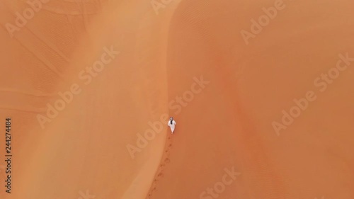 emirati man walking in massive sand dunes of Liwa desert, part of Empty Quarter desert