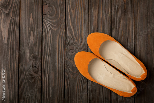 Orange women's shoes (ballerinas) on wooden background.