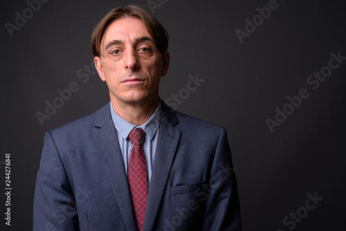 Face of mature handsome Italian businessman against gray background
