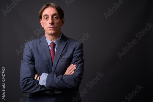 Mature handsome Italian businessman against gray background © Ranta Images