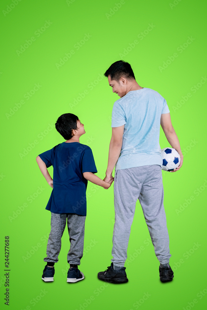 Fototapeta premium Young man holding a soccer ball with his son