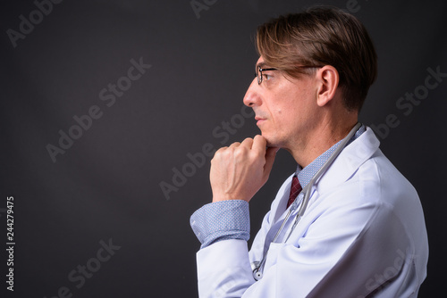 Profile view of mature handsome Italian man doctor thinking
