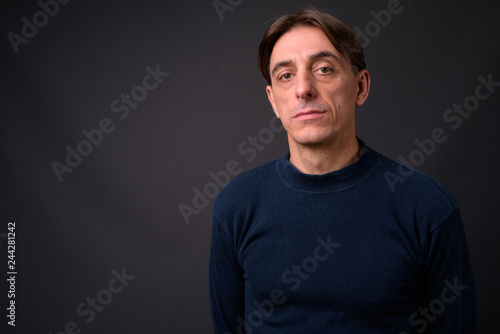 Mature handsome Italian man against gray background