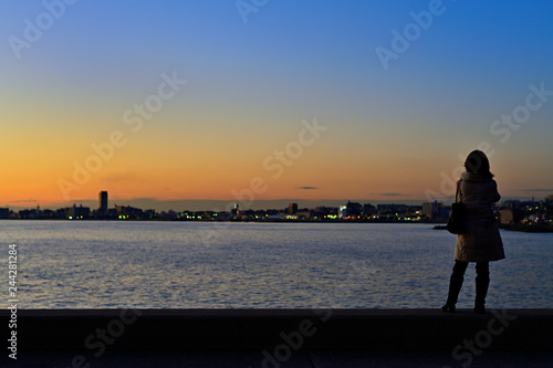 海岸の夕焼けを眺める女性