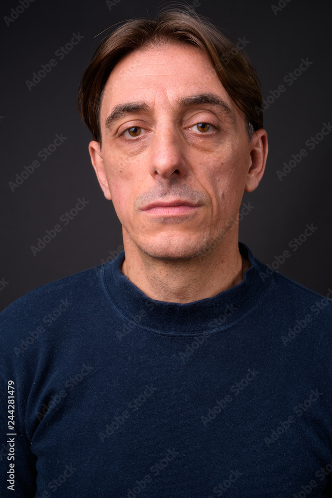 Face of mature handsome Italian man against gray background Face of mature handsome Italian man against gray background